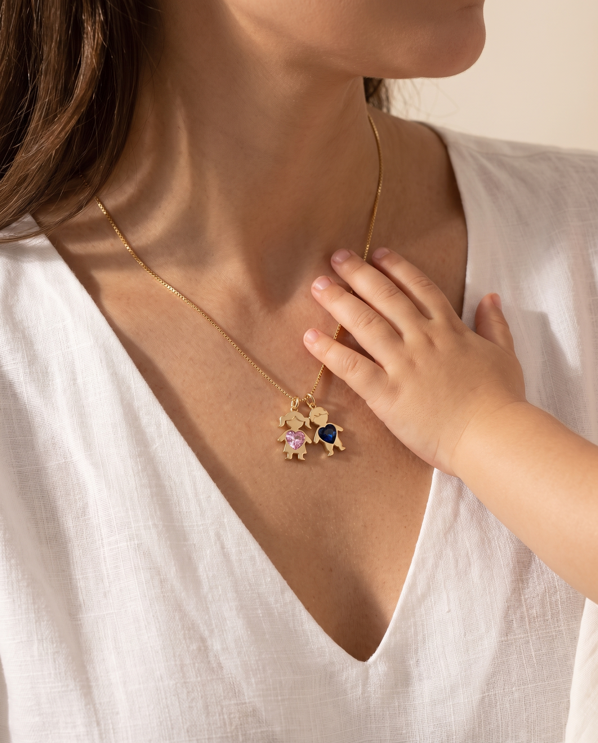 Collier Mes Enfants porté par une maman, la main de son enfant posée près du cou